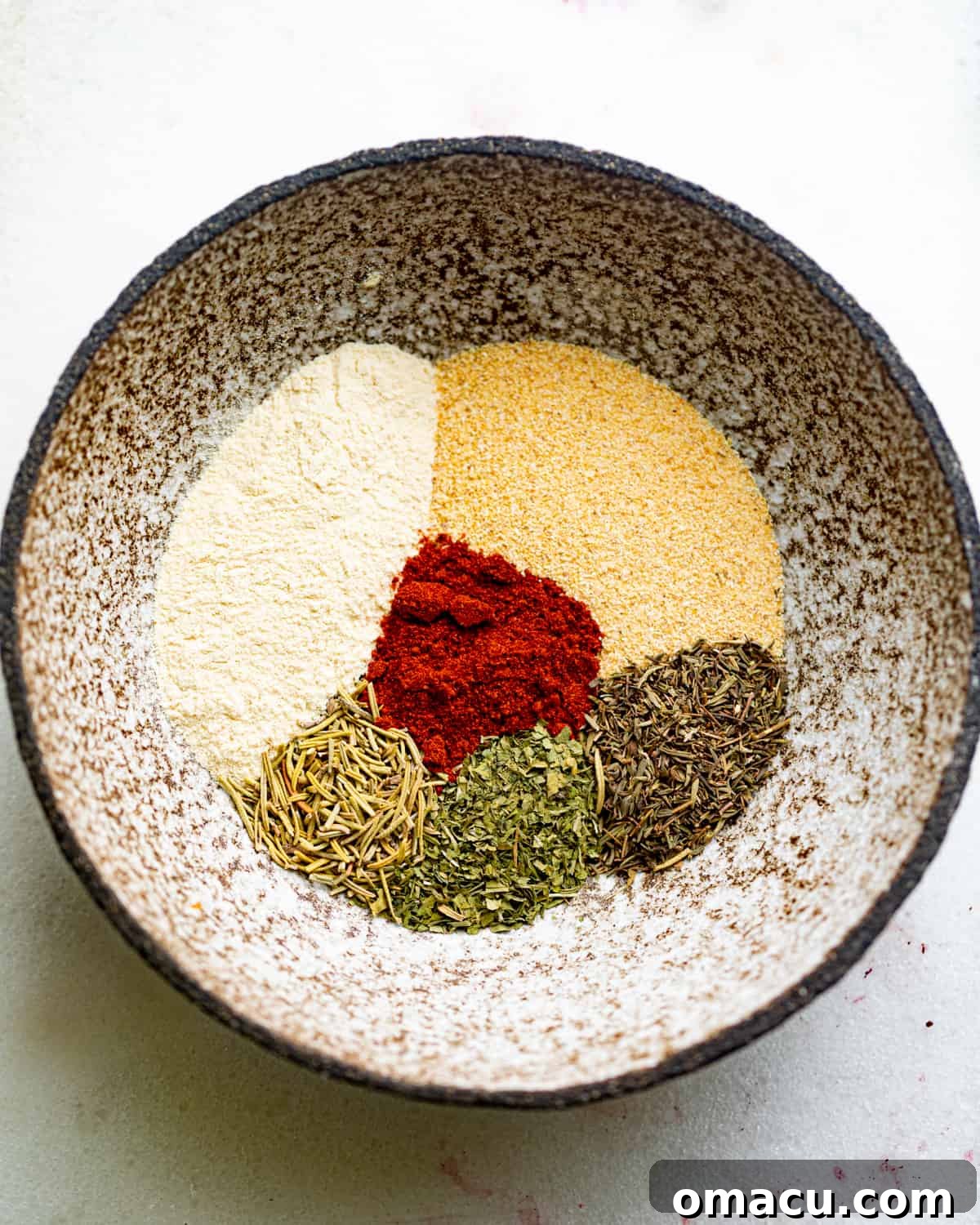 A small white bowl filled with a rich, reddish-brown homemade pot roast seasoning blend, ready to be used.