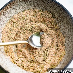 A small white bowl containing the homemade pot roast seasoning, with a wooden spoon resting inside.