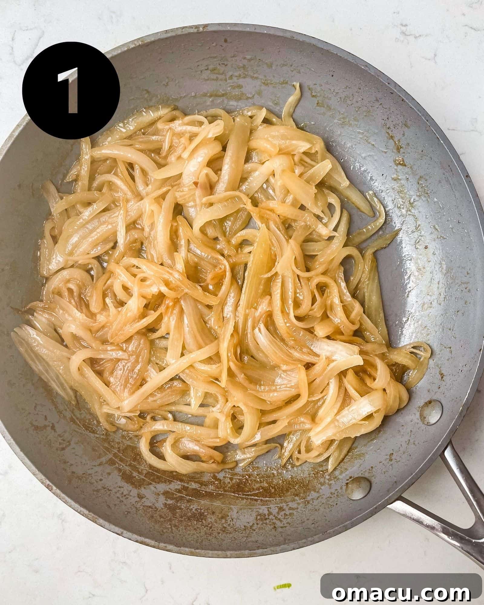 Thinly sliced onions caramelizing in a skillet, turning golden brown and soft.