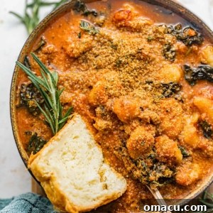 tomato gnocchi soup in a bowl with a piece of bread.