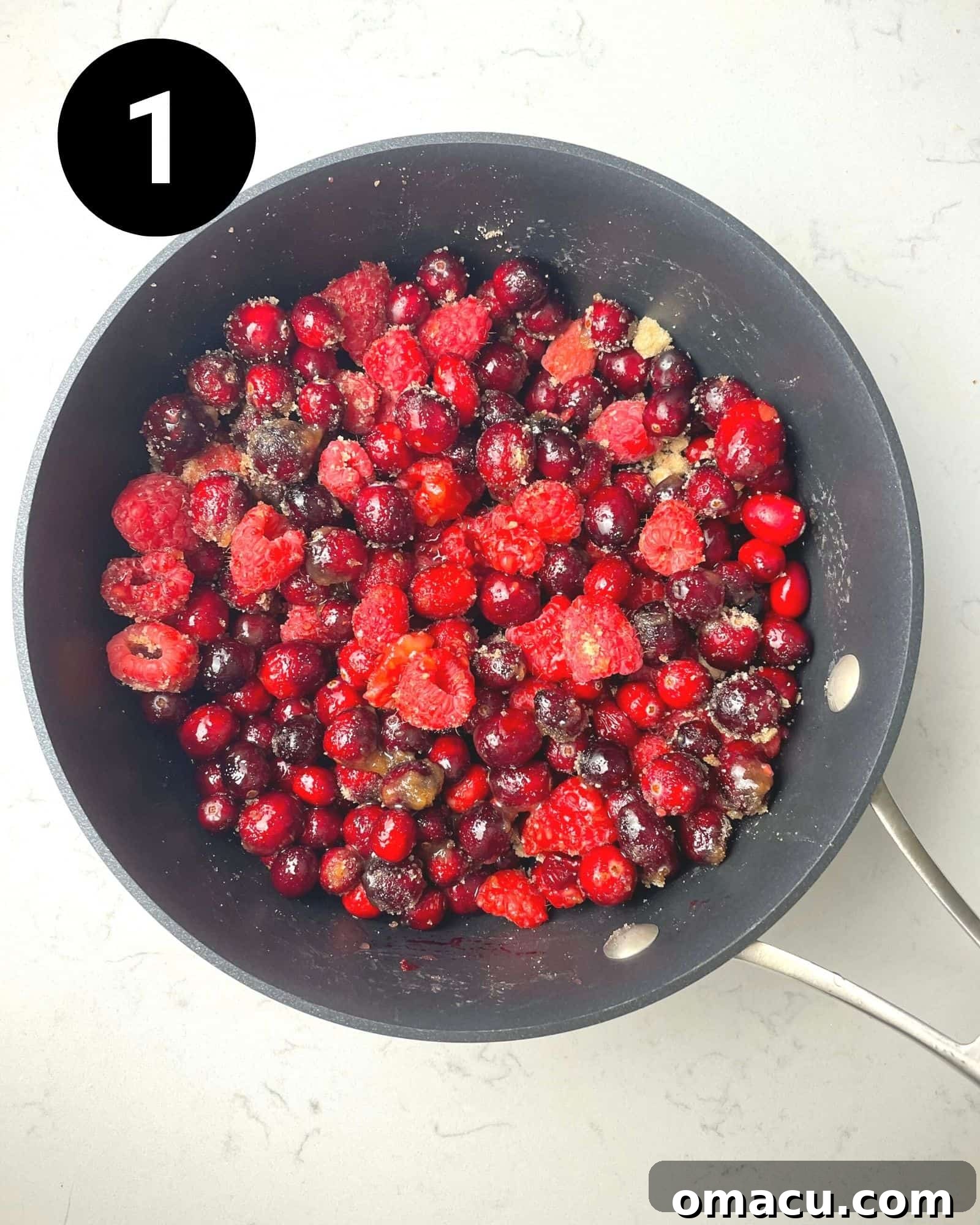 Fresh cranberries, raspberries, lemon juice, and brown sugar simmering together in a saucepan.
