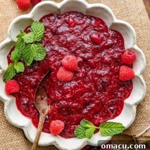 cranberry raspberry sauce in a bowl topped with fresh raspberries.