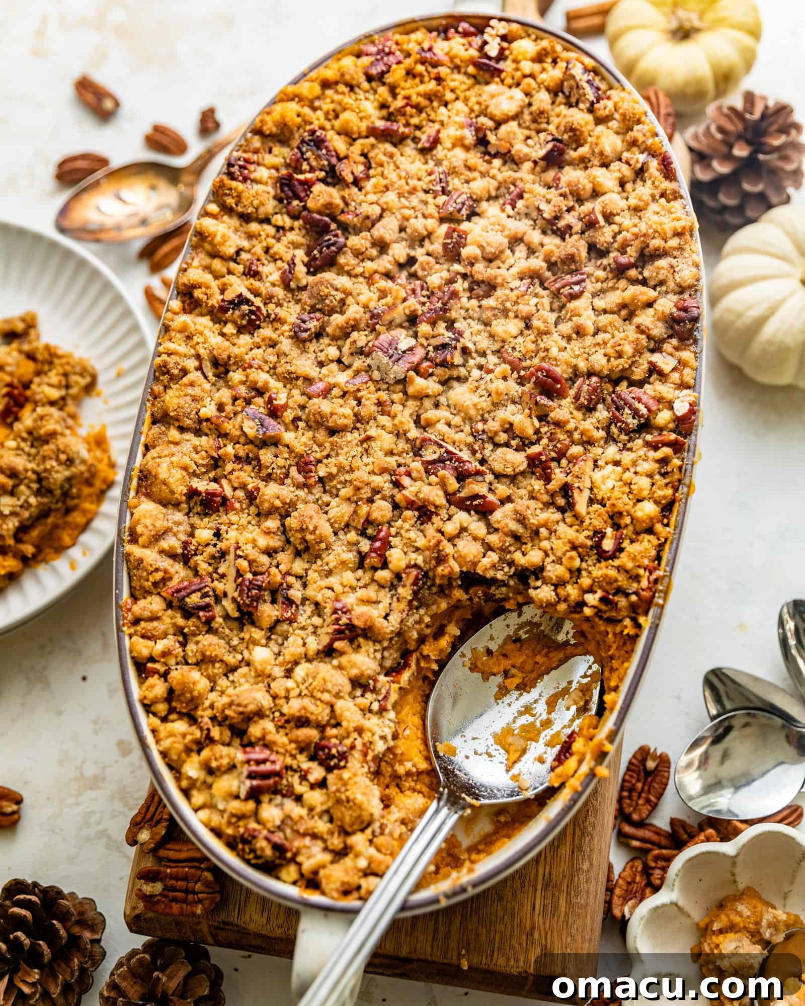 A generous scoop of Bourbon Sweet Potato Casserole, showcasing its creamy interior and crunchy pecan topping, served with a decorative spoon.