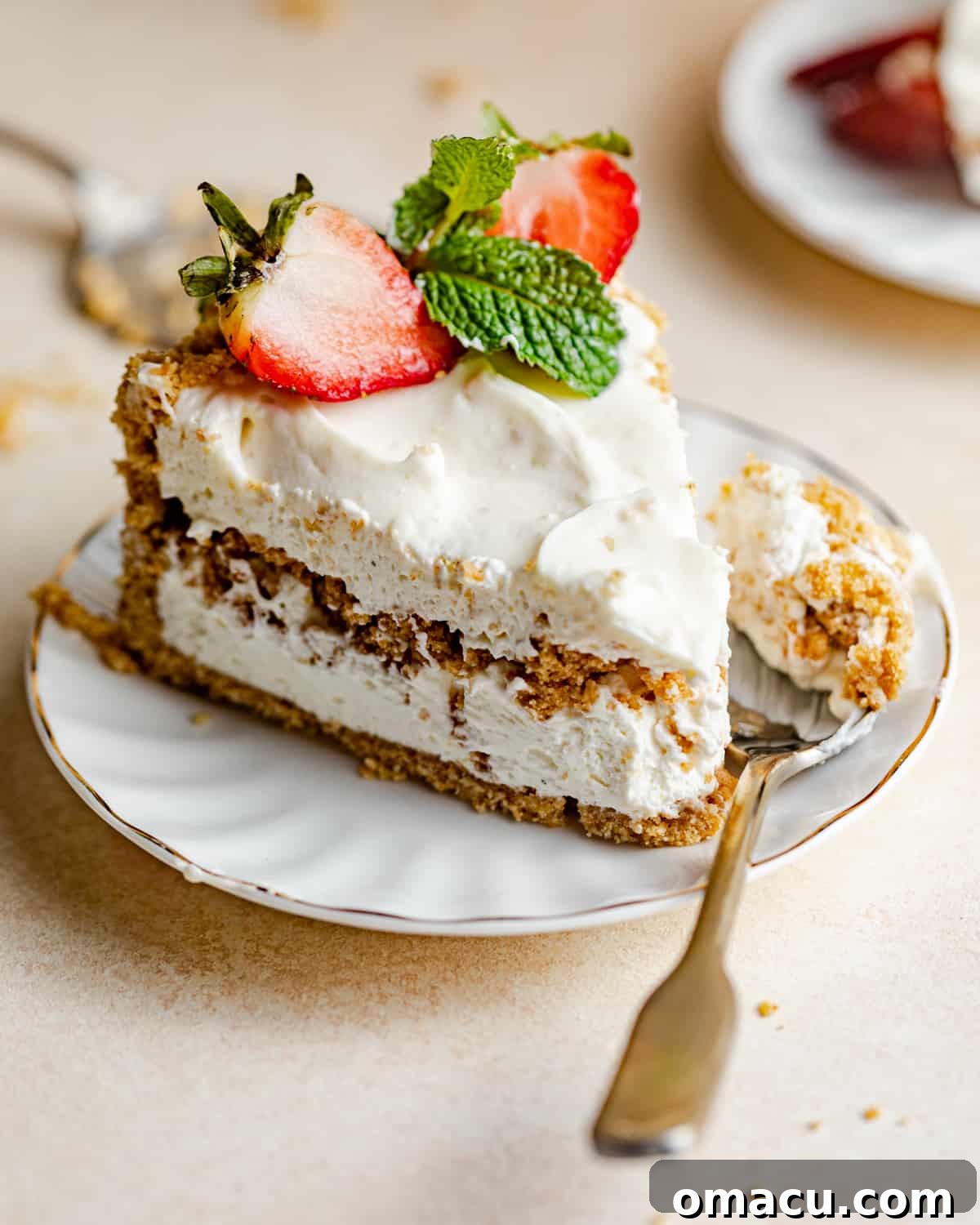 A perfectly sliced Philadelphia No-Bake Cheesecake on a white plate, showcasing its creamy texture and graham cracker layers.