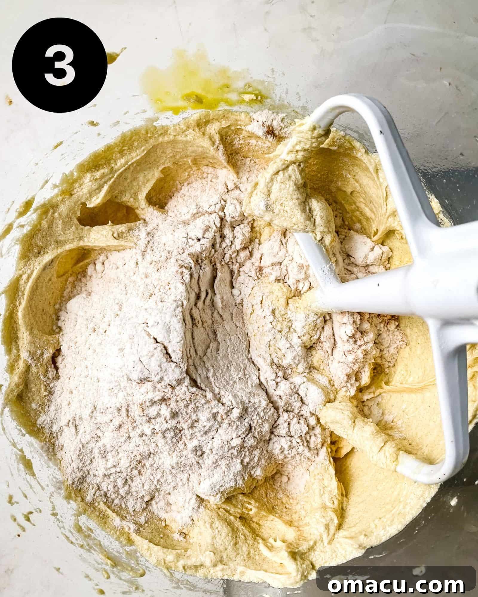 The combined wet and dry ingredients for the cardamom cake batter, appearing smooth and fully mixed in a large bowl.