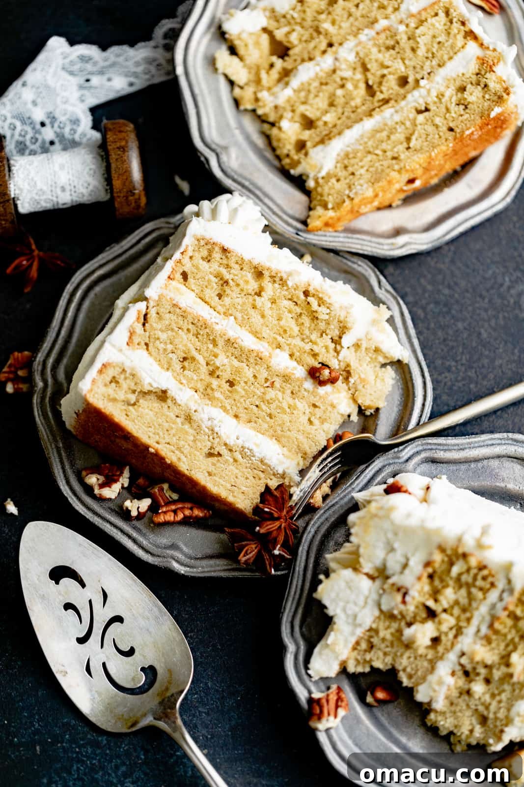 Slices of cardamom cake garnished with chopped pecans on a white plate, showcasing the beautiful layers.