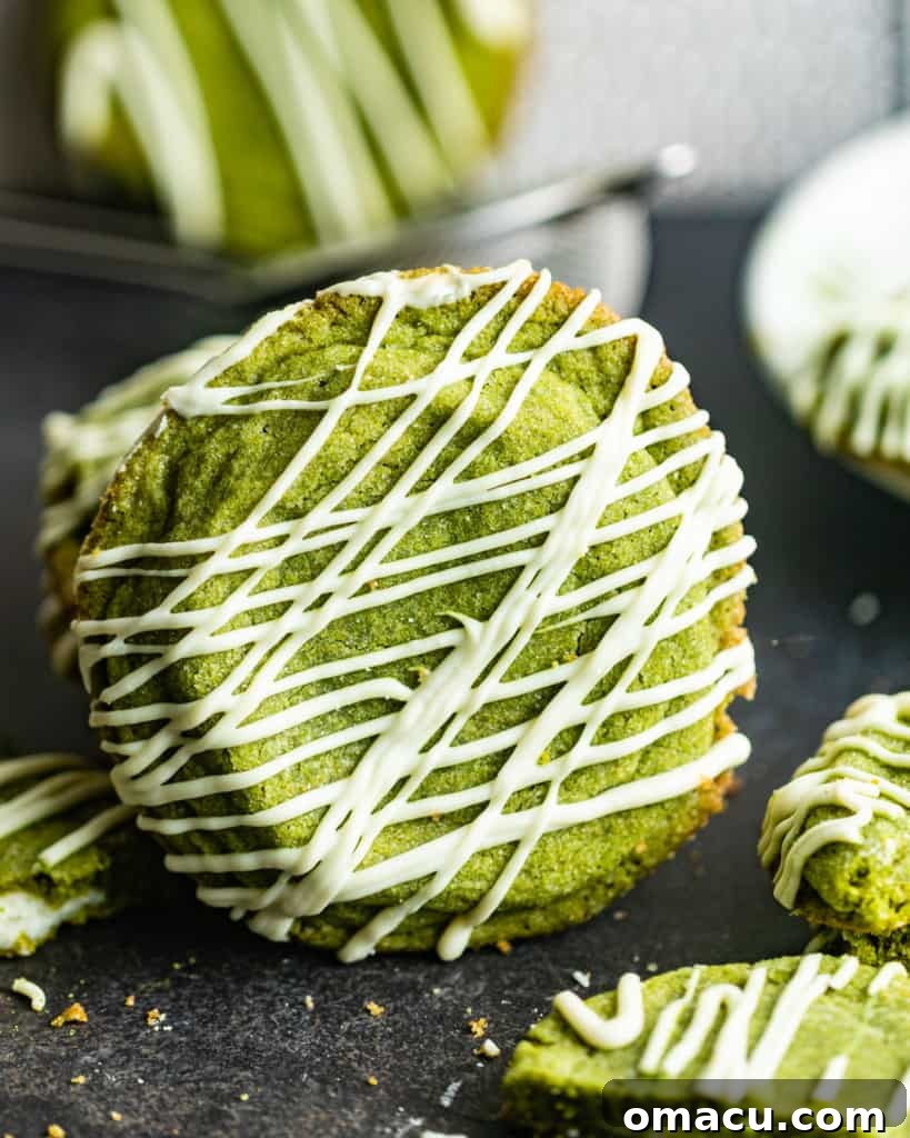 A close-up shot of a beautifully presented matcha cookie, showcasing its vibrant green color and the rich, gooey white chocolate cream cheese filling peeking out from its soft center.