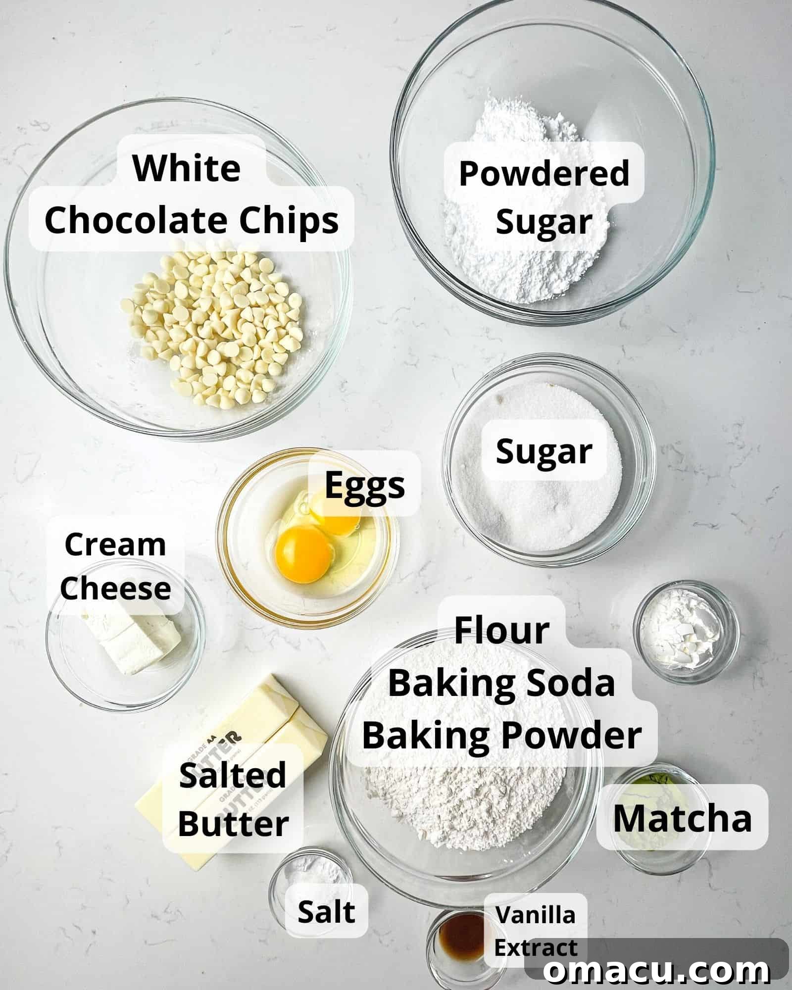 A beautiful flat lay of all the essential ingredients needed to bake these delightful matcha cookies: powdered sugar, white chocolate chips, granulated sugar, matcha powder, vanilla extract, eggs, all-purpose flour, baking soda, baking powder, butter, cream cheese, and a pinch of salt.