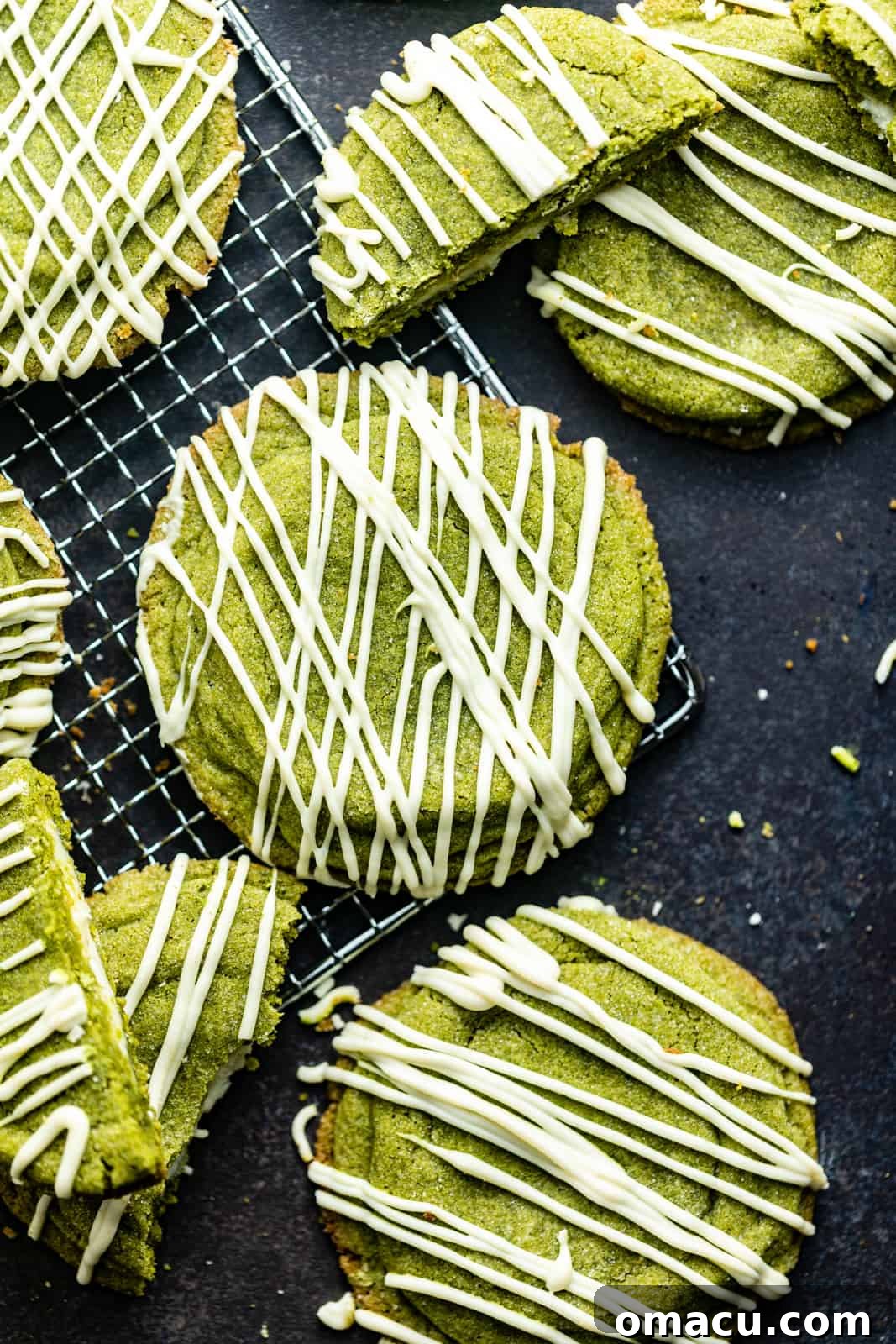 Freshly baked matcha cookies cooling on a wire rack after being removed from the oven.