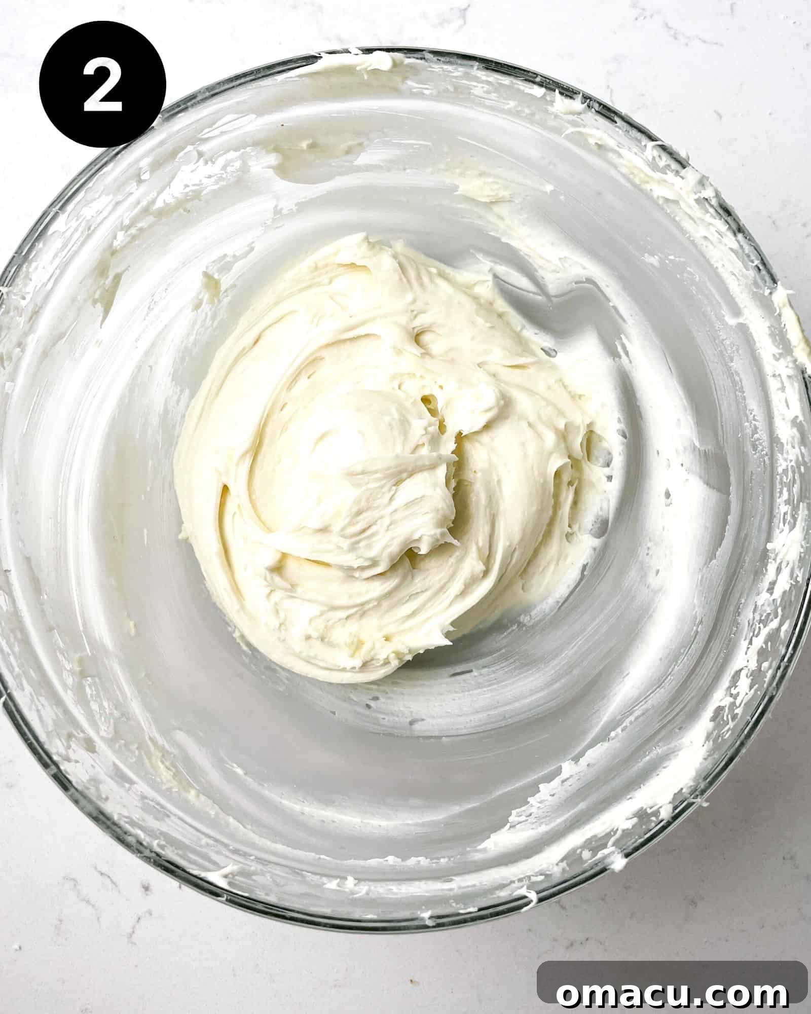 A creamy mixture of cream cheese and white chocolate, perfectly whisked together in a bowl for the cookie filling.