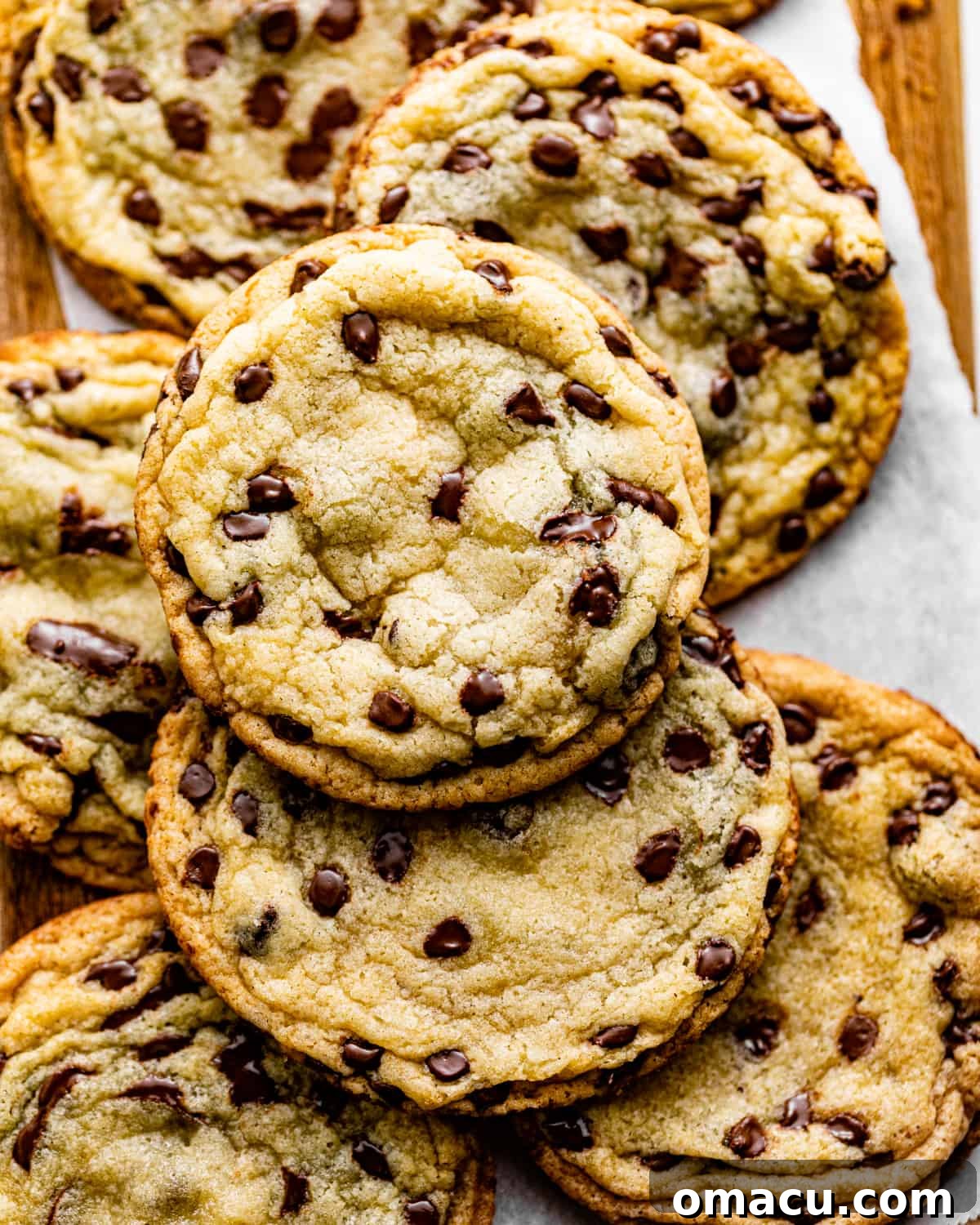 Golden-brown chocolate chip sugar cookies, without brown sugar, cooling on a rustic wooden board.