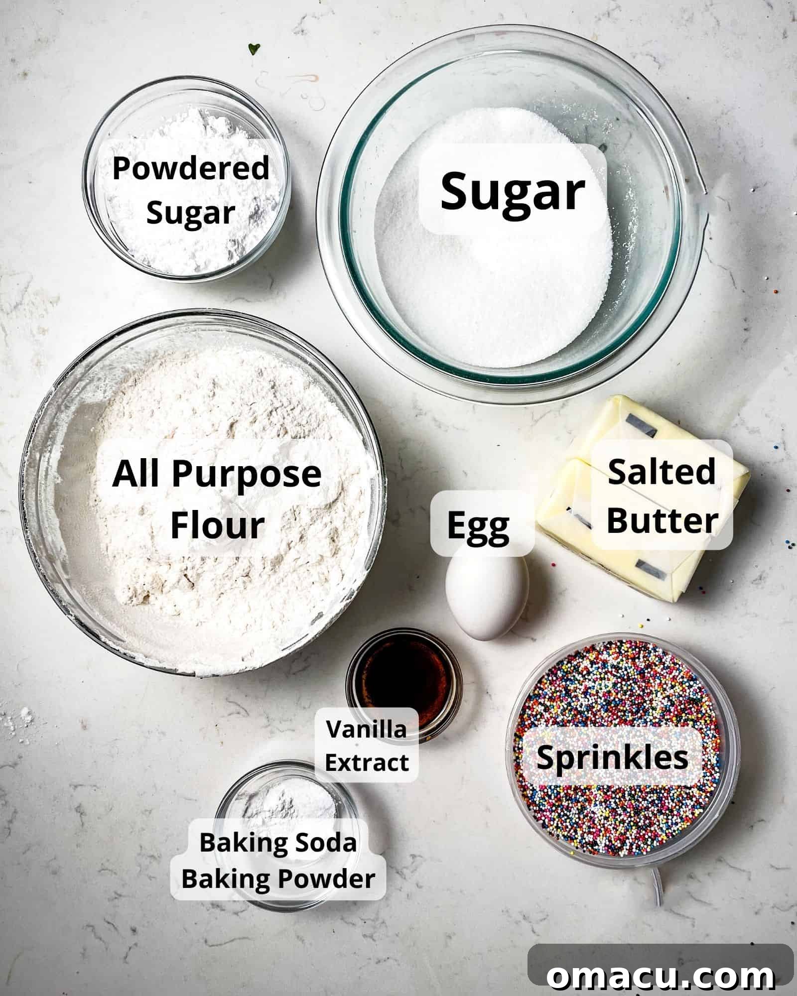 Close-up of essential ingredients for sprinkle sugar cookies: powdered sugar, granulated sugar, all-purpose flour, egg, softened butter, baking soda, baking powder, vanilla extract, and rainbow sprinkles arranged on a rustic surface.