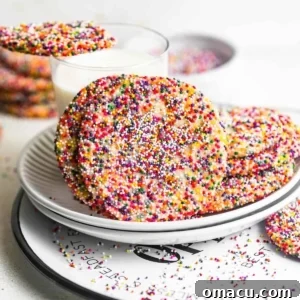 Delicious sprinkle sugar cookies placed in front of a glass of milk, perfect for a sweet treat.