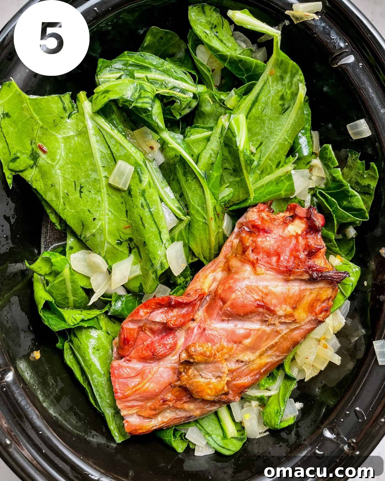 Smoked meat and shredded collard greens combined in a slow cooker, ready for the long cooking process.
