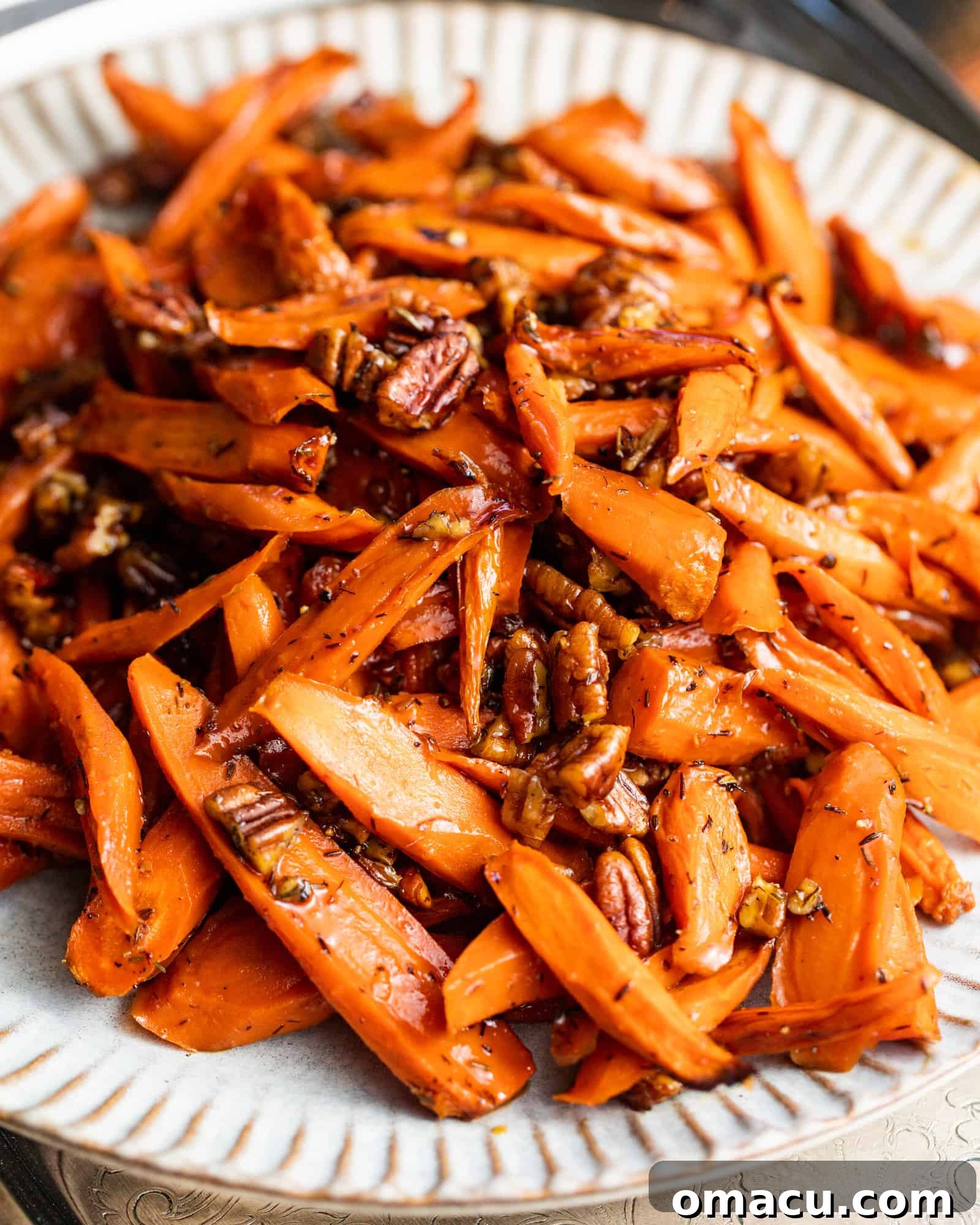 A vibrant platter of brown sugar honey glazed carrots, perfectly roasted and arranged on a white plate, ready to be served.
