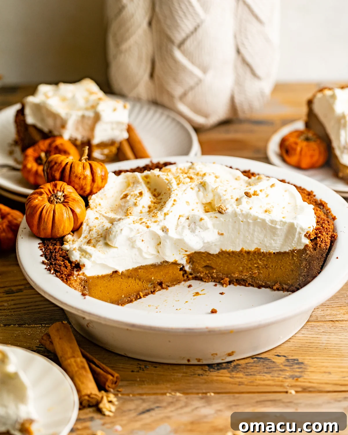 A beautifully baked pumpkin pie with a graham cracker crust, presented in a pie dish and generously topped with a swirl of whipped cream.