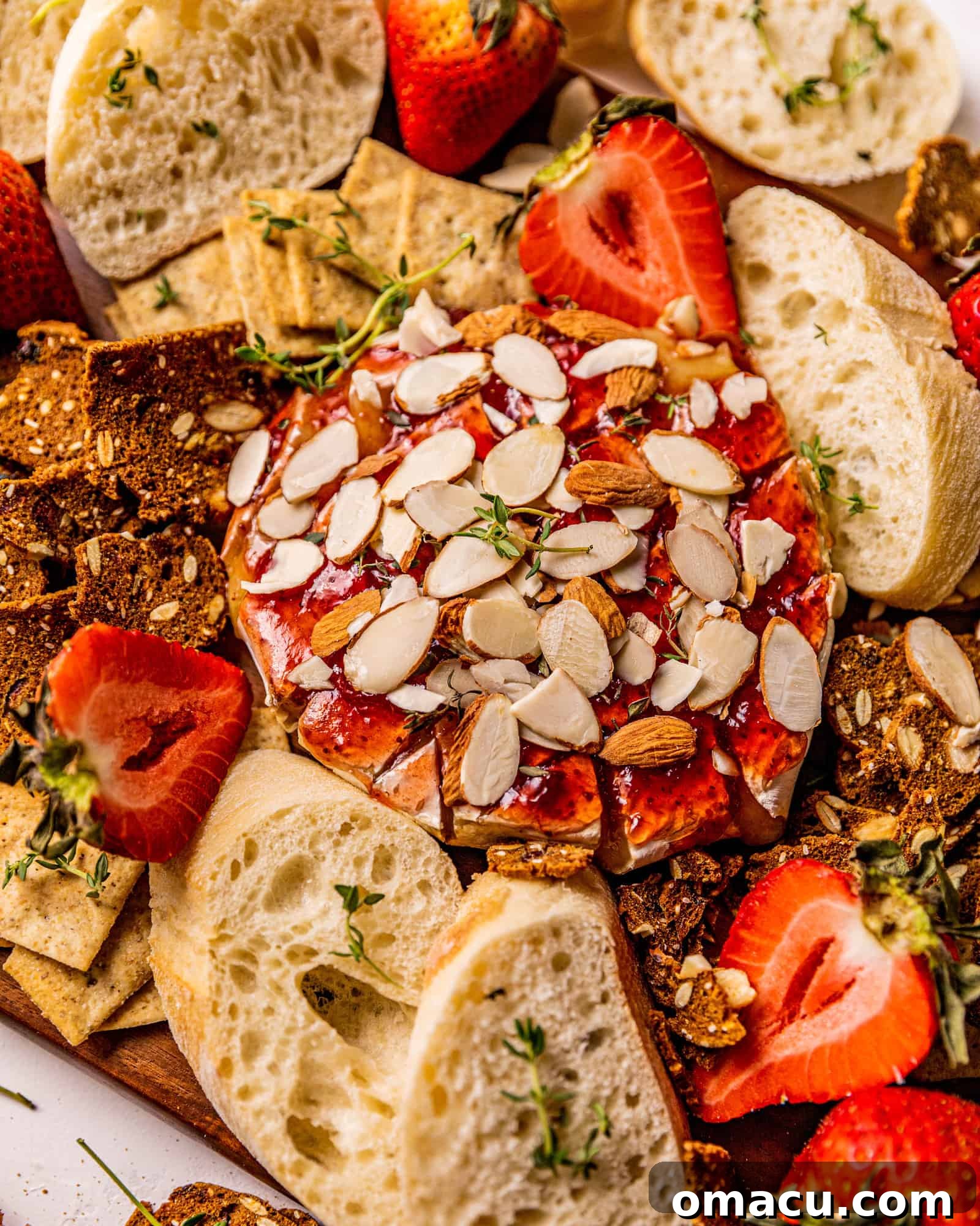 A perfectly golden baked brie, generously topped with glistening jam and a sprinkle of almonds, ready to be served as an exquisite appetizer.
