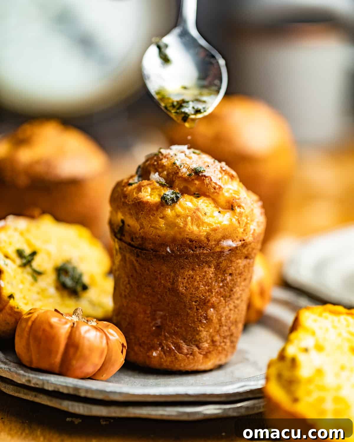 A single, perfectly golden pumpkin popover, freshly baked and presented on a pristine white plate, ready to be enjoyed.