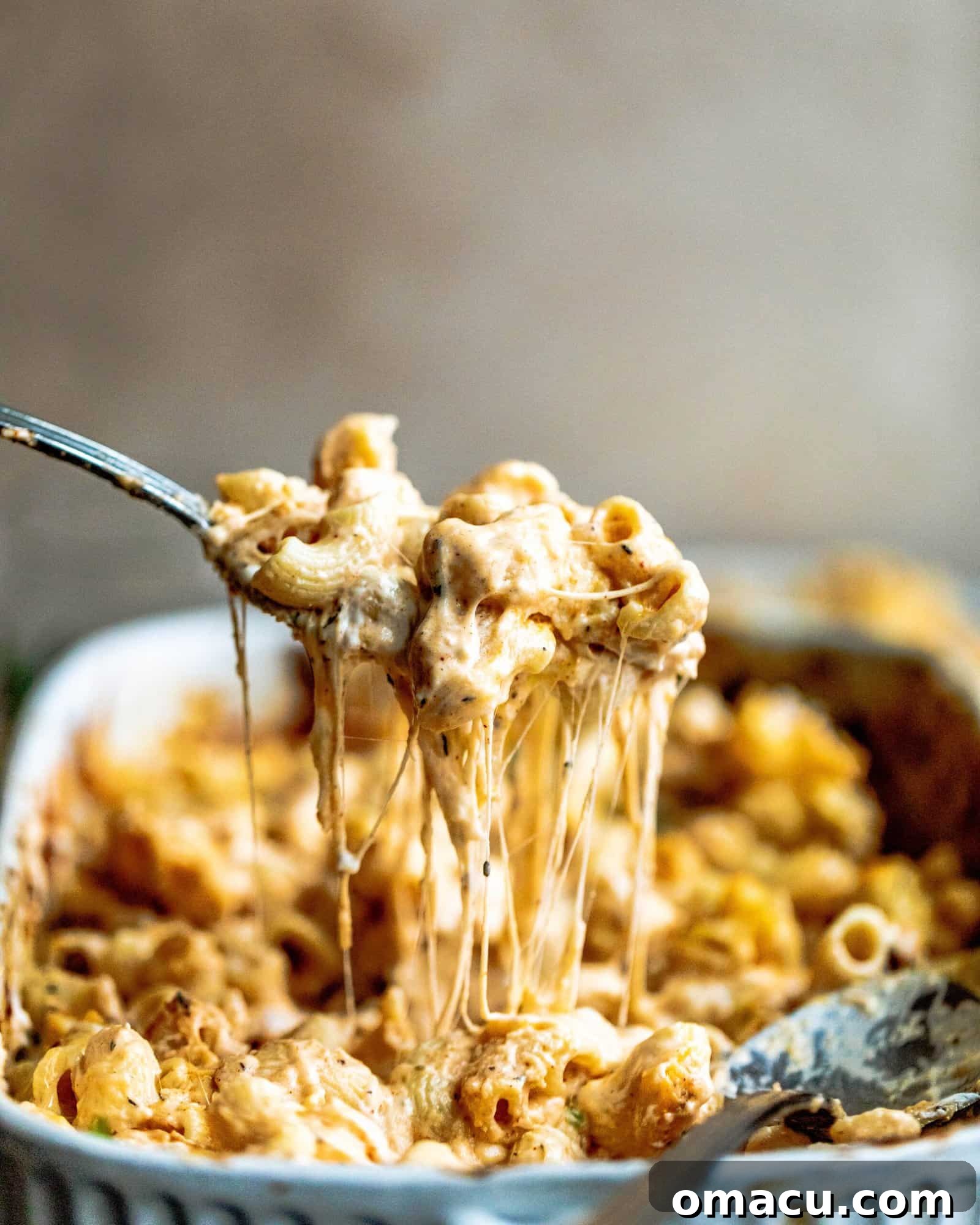 An irresistible cheese pull from a spoon, demonstrating the decadent, gooey texture of freshly baked macaroni and cheese.