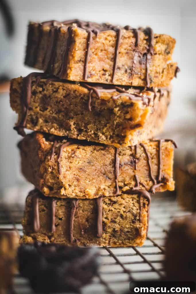 A close-up shot of a freshly baked Miso Prune Blondie, highlighting its rich, fudgy texture and glistening chocolate drizzle, inviting a delicious bite.