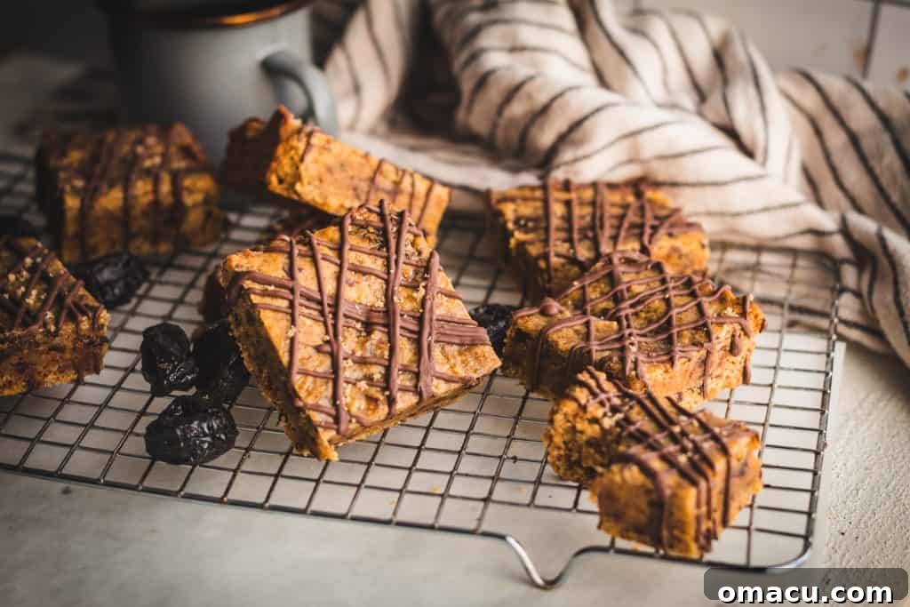 A close-up of a single Miso Prune Blondie, expertly sliced and showcasing the intricate chocolate drizzle atop its dense, moist interior.