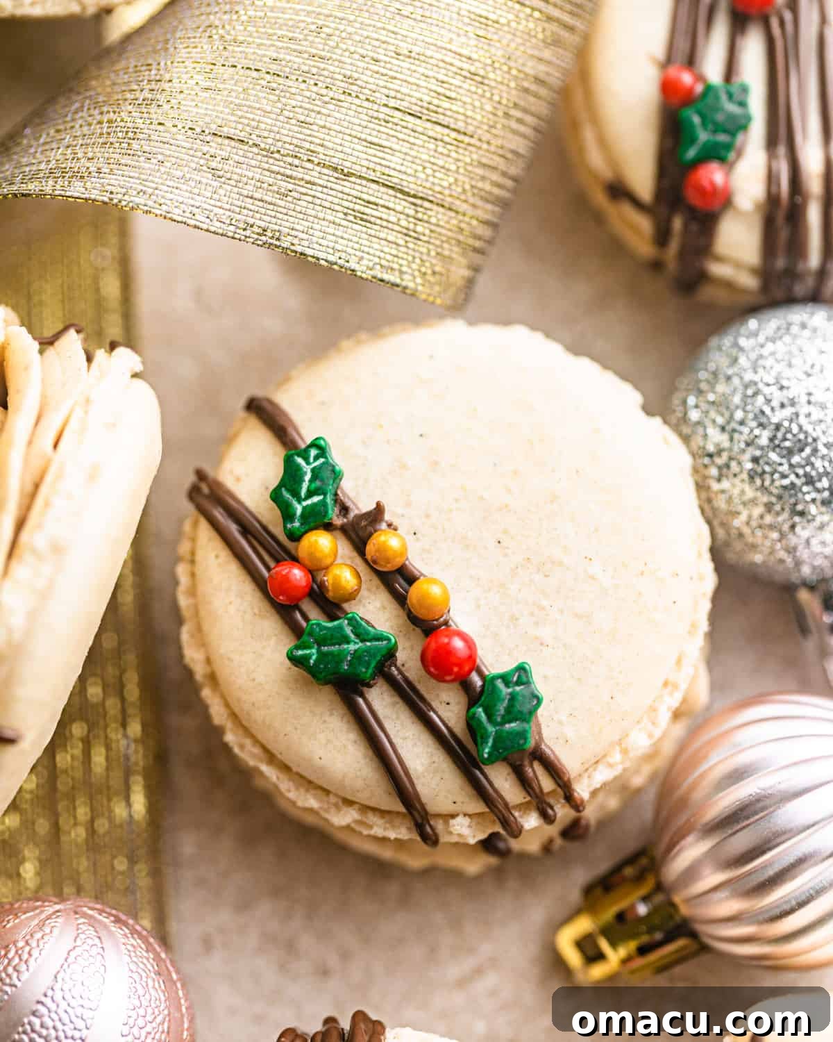 finished gingerbread macarons on a table adorned with Christmas ornaments and ribbons.