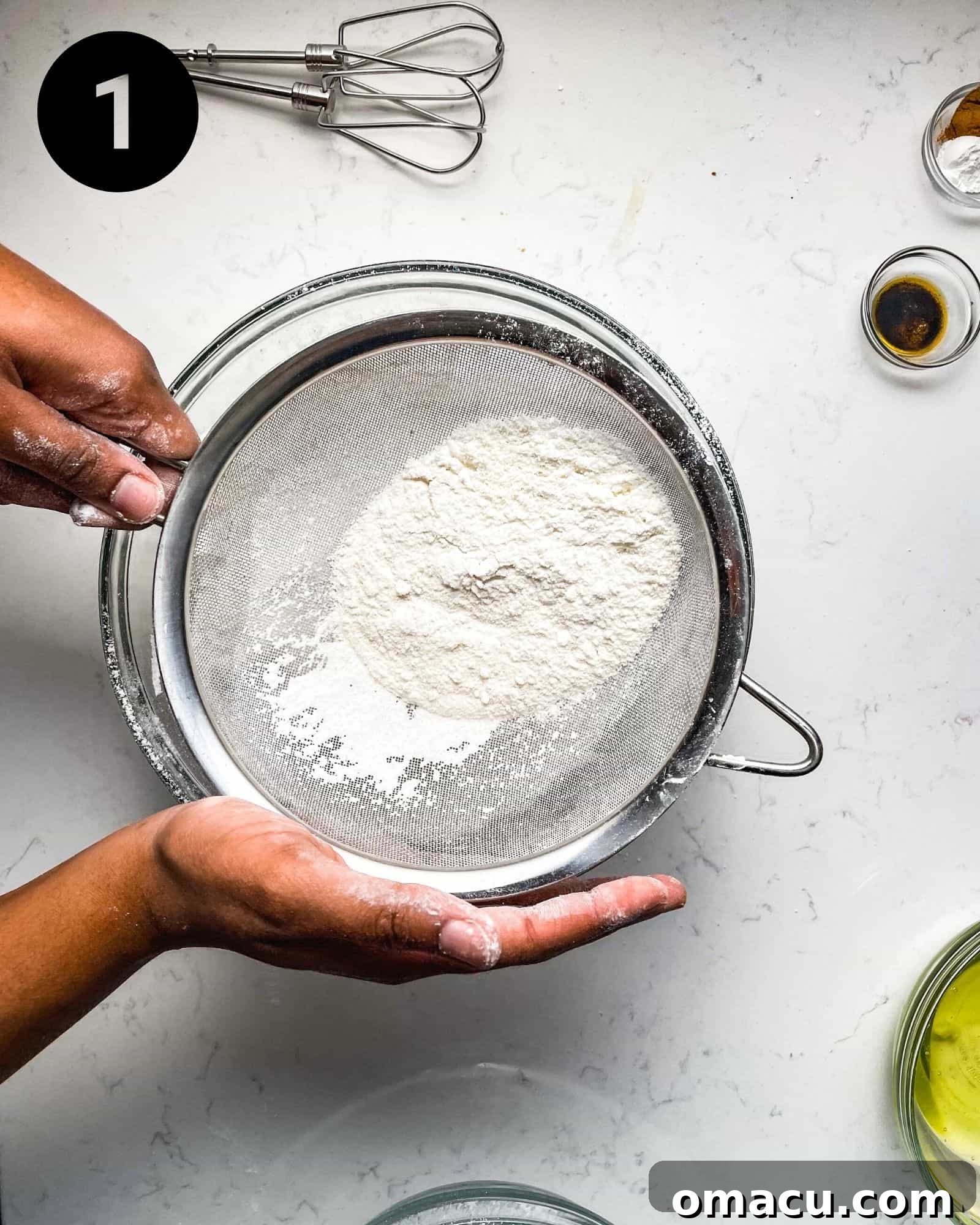 sifting almond flour into a bowl to prepare macaron batter.