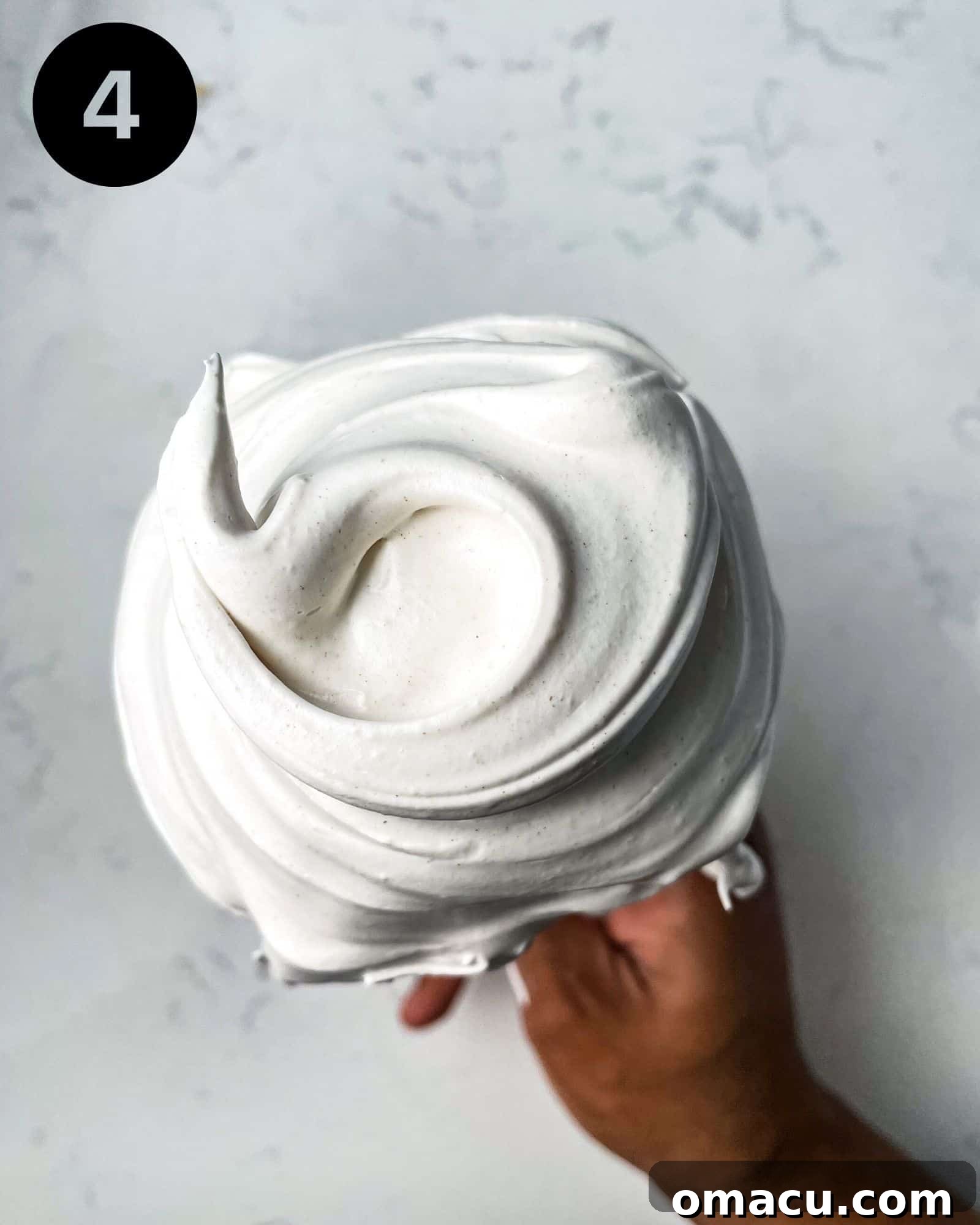 meringue on a whisk demonstrating the perfect stiff peak consistency.