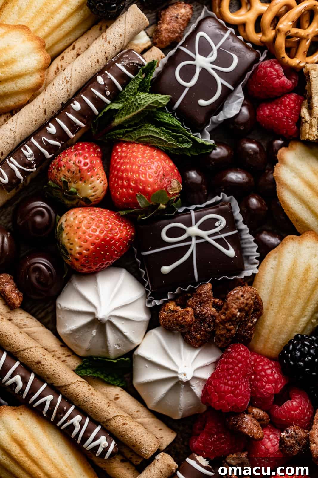 A vibrant dessert charcuterie board featuring an enticing mix of candies, various cookies, and fresh, colorful fruit slices artfully arranged on a large serving platter.
