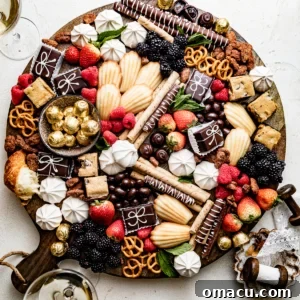 A dessert charcuterie board abundantly laden with sweet treats, fruits, and dips, displayed on a clean white surface.