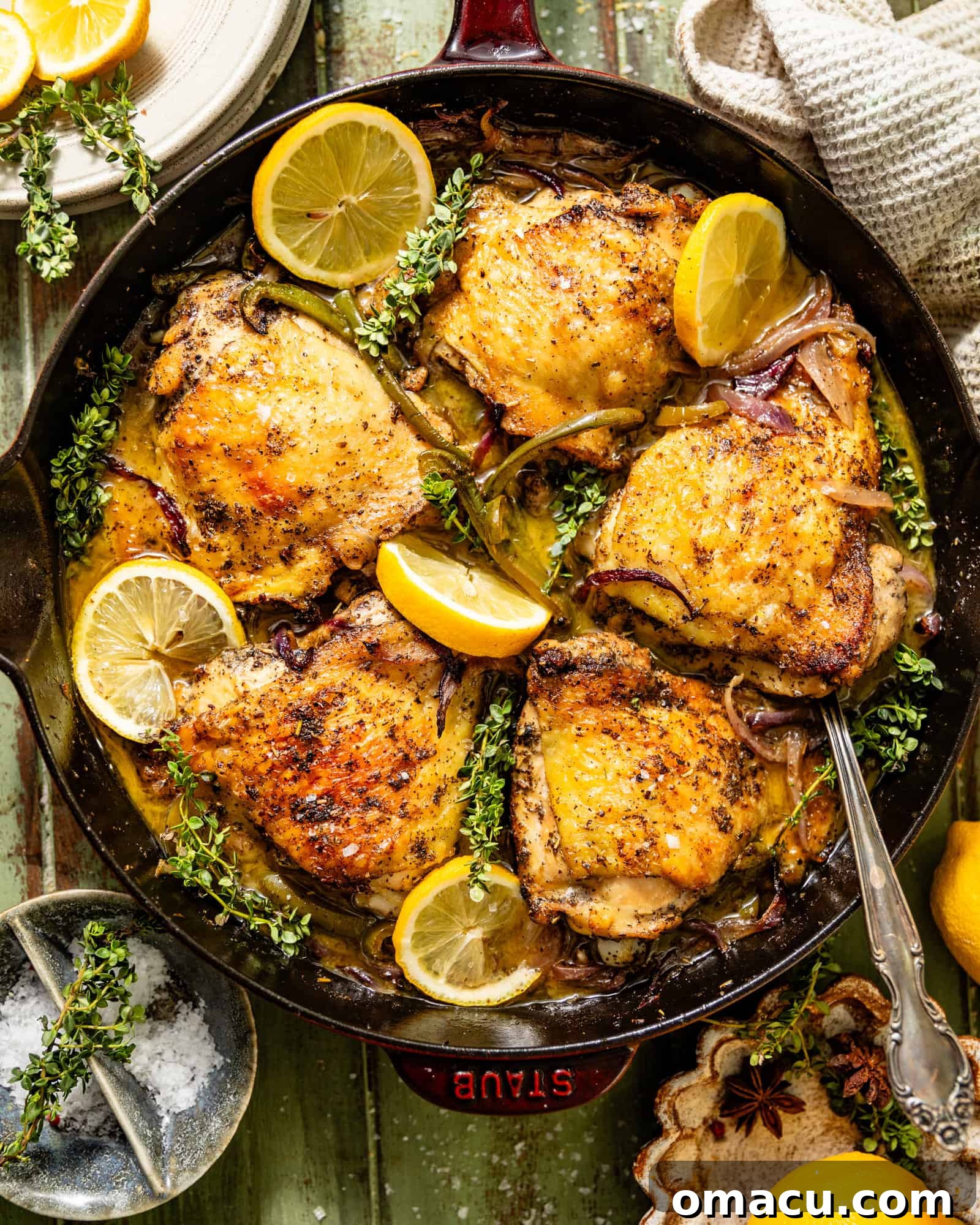 Overhead shot of perfectly cooked skillet chicken thighs in a cast iron pan with a serving spoon, ready to eat.