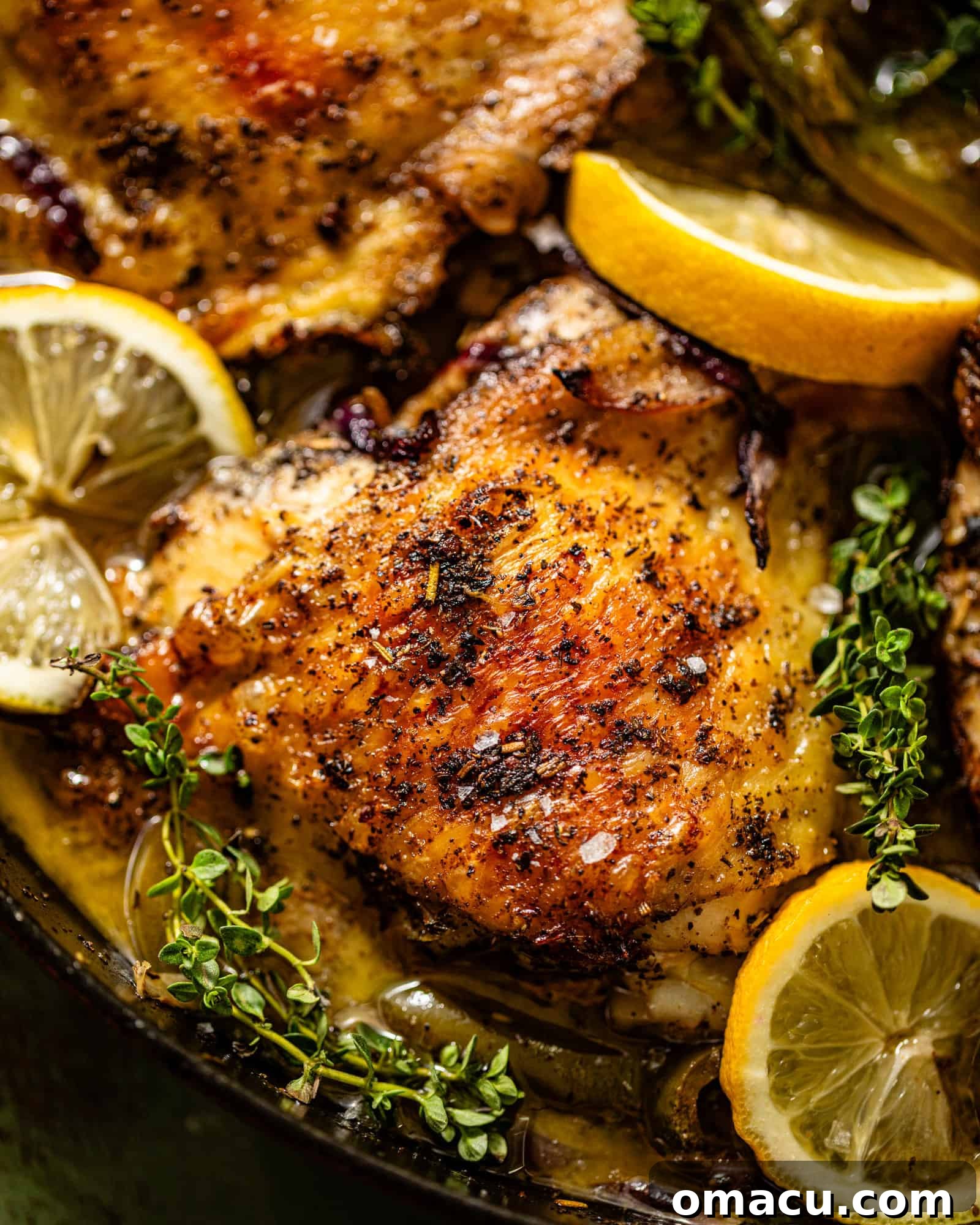 Close-up of a perfectly cooked, golden-brown chicken thigh resting in a cast iron skillet.