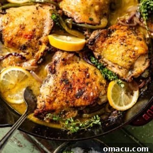 seared chicken in a skillet with fresh herbs, sliced lemon, and a serving spoon.