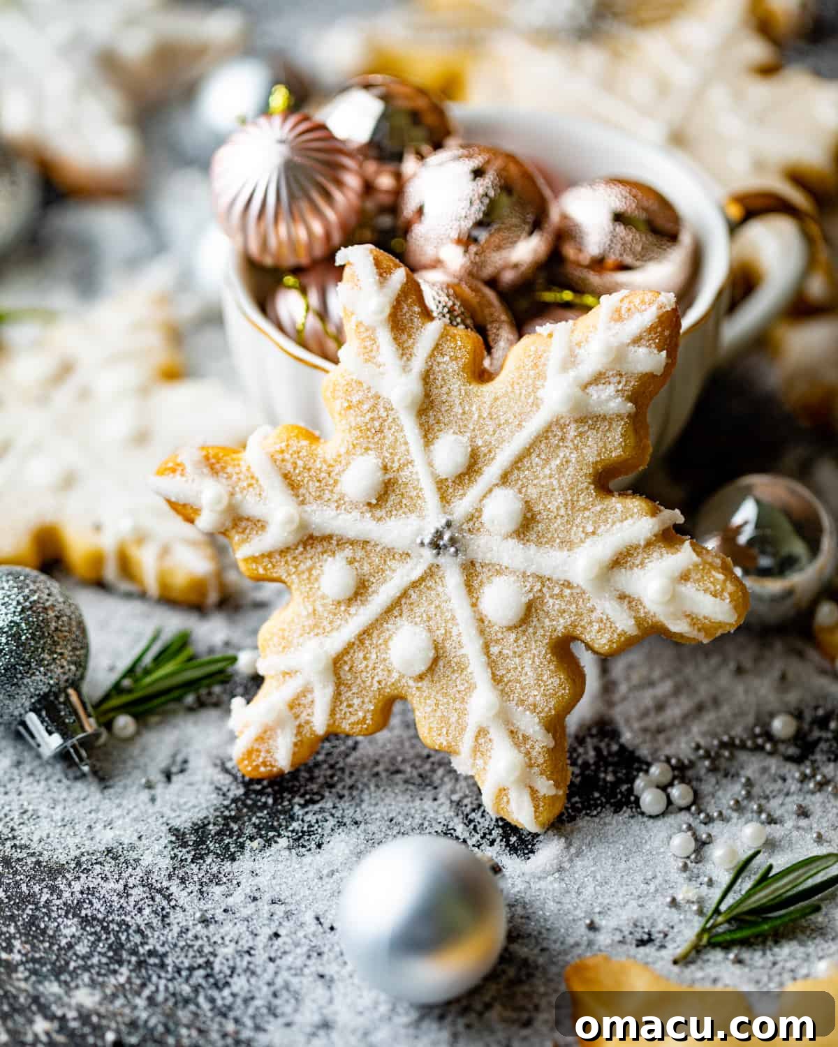 A perfectly piped snowflake shortbread cookie standing elegantly on a wooden table, surrounded by twinkling Christmas lights and festive ornaments, evoking a cozy holiday atmosphere.