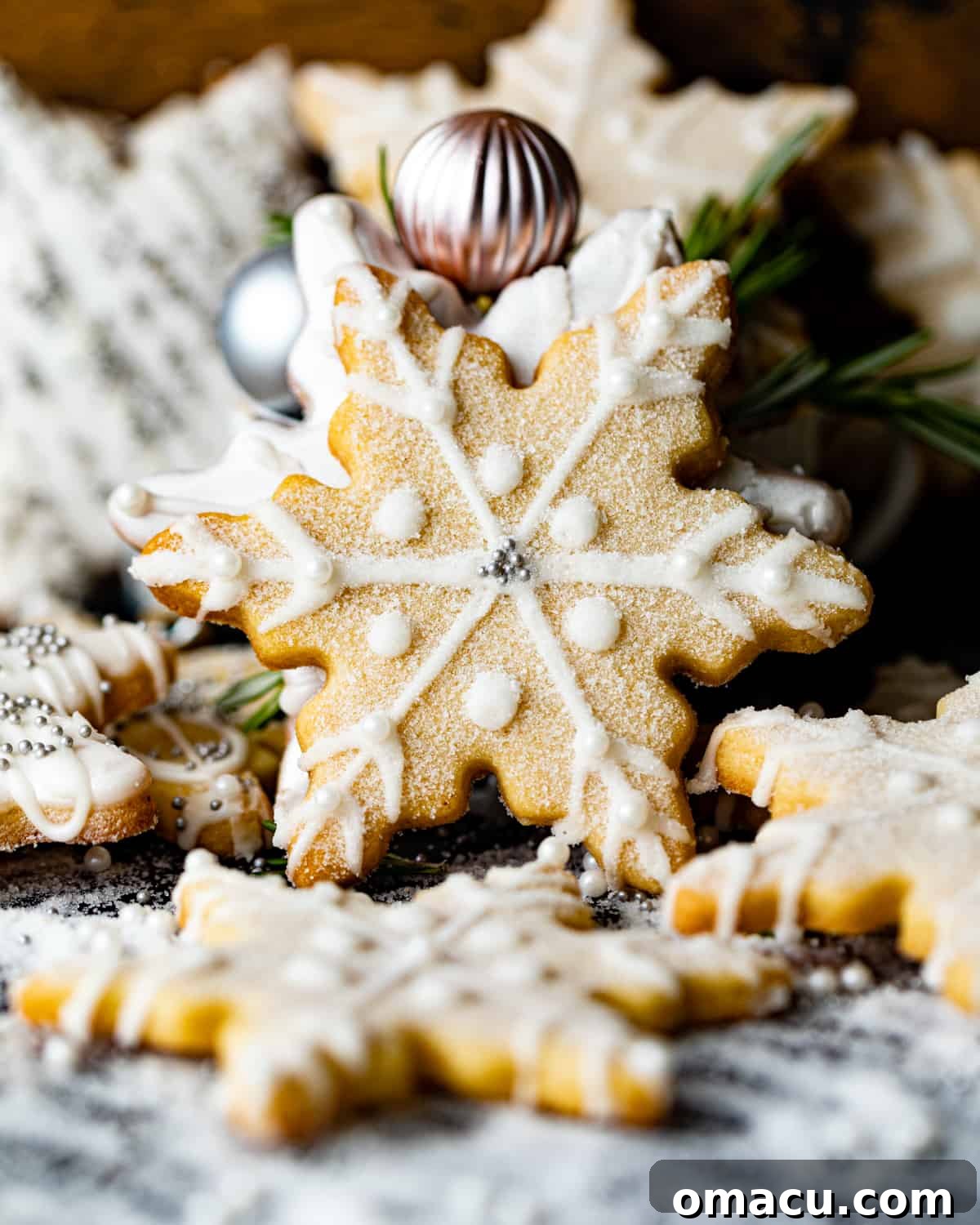 A festive spread of beautifully decorated snowflake shortbread cookies, artfully scattered on a surface, showcasing various intricate royal icing designs and optional sprinkles.
