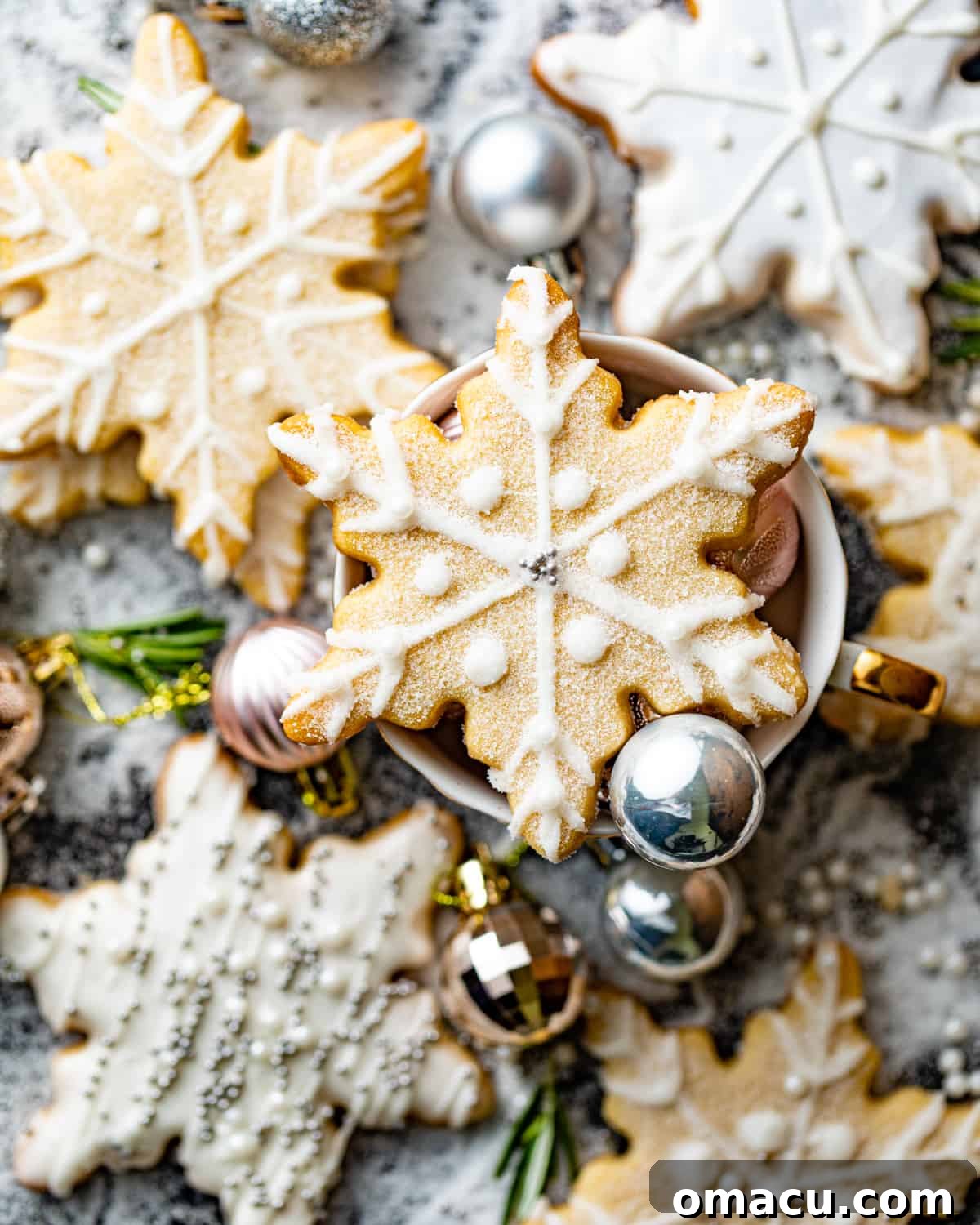 An artfully arranged collection of finished snowflake shortbread cookies displayed on a rustic wooden table, highlighting their intricate royal icing designs and golden-brown edges.