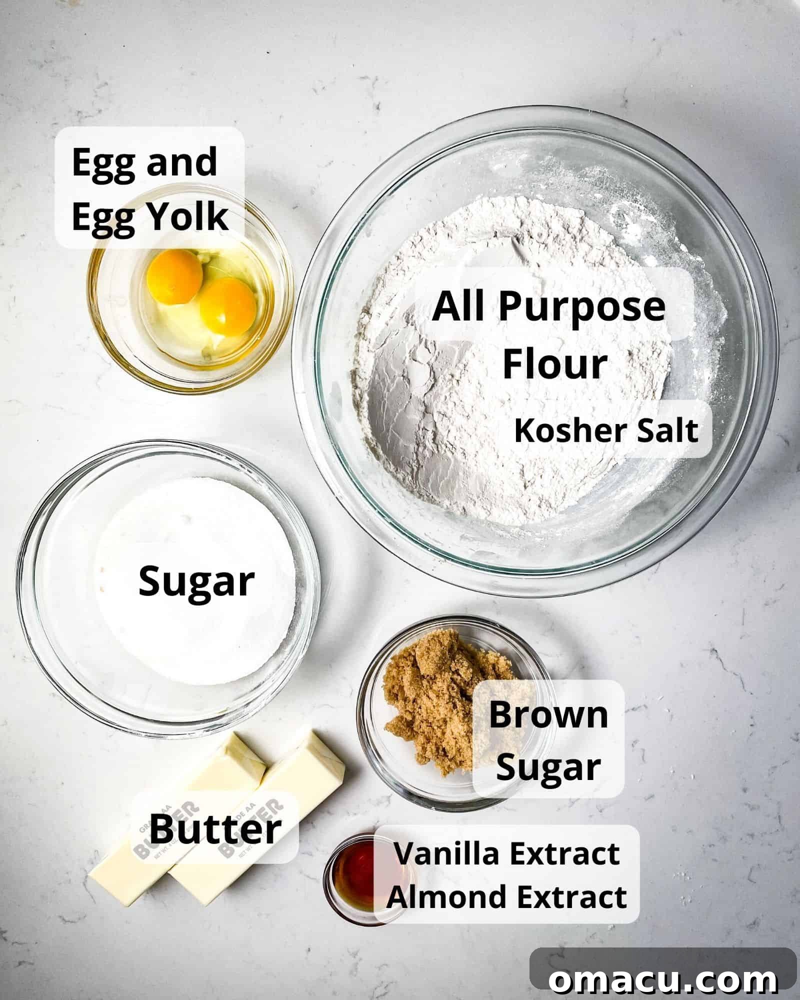 A meticulously arranged flat lay of all the essential ingredients required to bake delicious snowflake shortbread cookies, including flour, salt, egg, egg yolk, granulated sugar, brown sugar, vanilla extract, almond extract, and softened butter, showcasing their freshness and readiness.