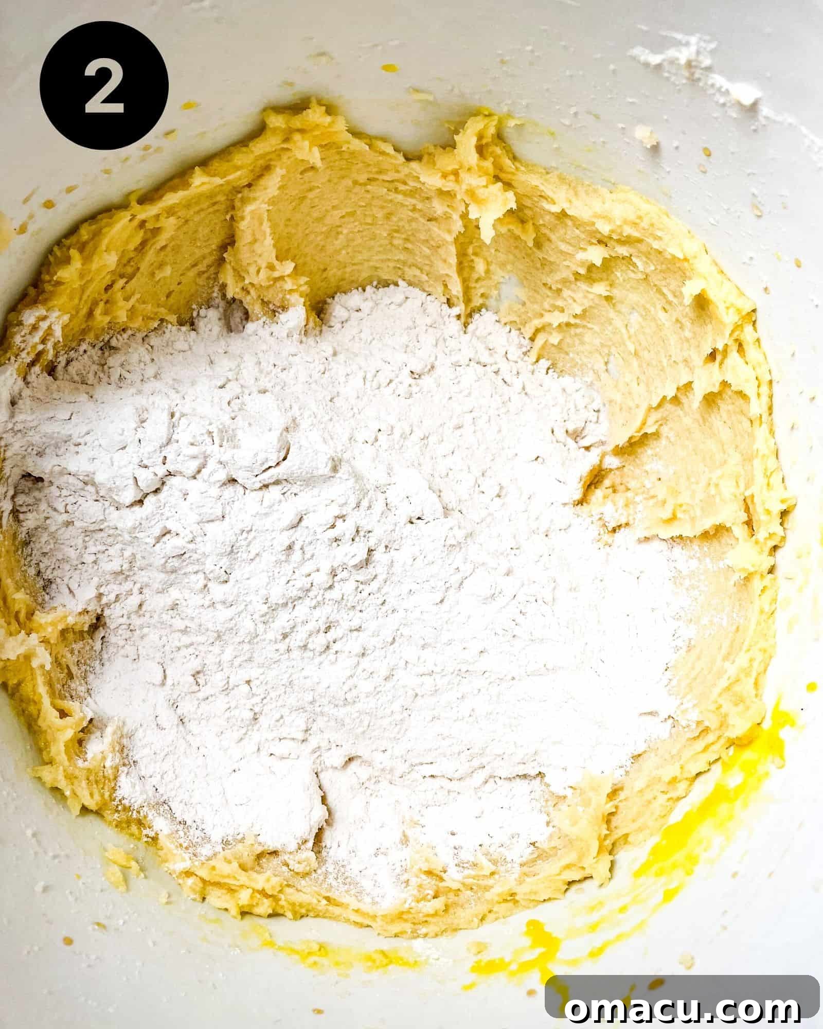 All-purpose flour and salt are added to the wet ingredients in a mixing bowl, gently combined to form the shortbread cookie dough.