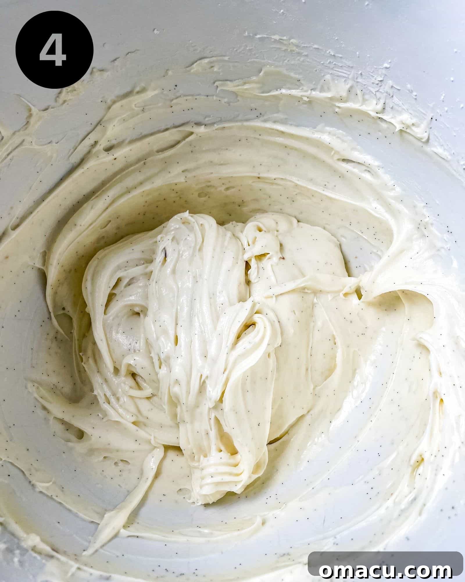 Creamy, smooth homemade cream cheese icing mixed together in a bowl, covered and ready for use.