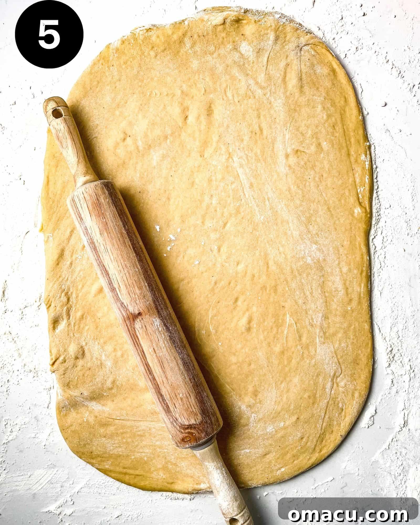 Cinnamon roll dough rolled out perfectly into a 12x18 inch rectangle on a floured work surface.