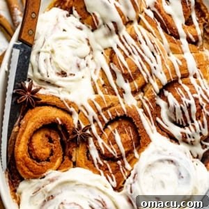 cinnamon rolls in a baking dish covered in a cream cheese icing.