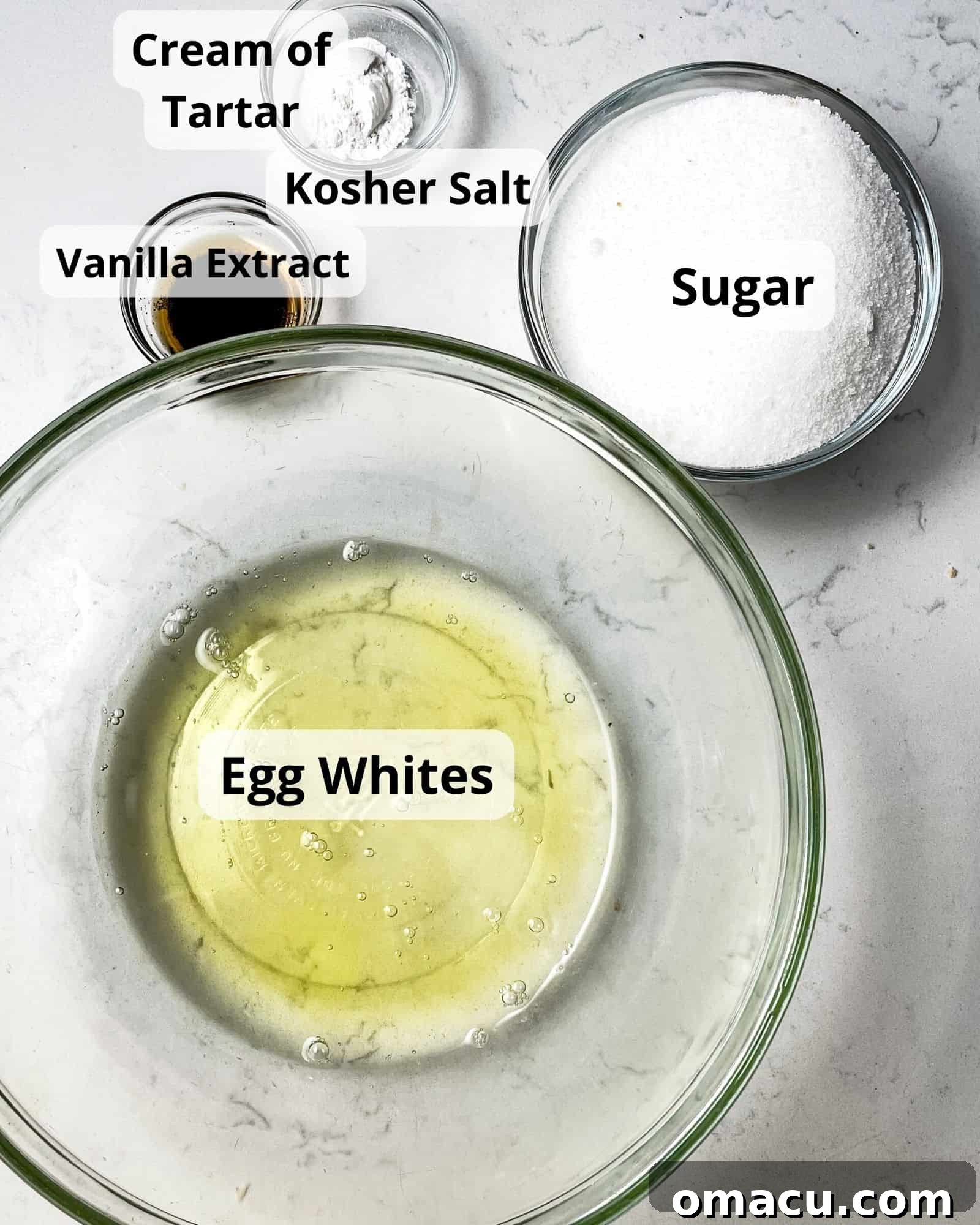 ingredients to make meringue cookies - egg whites, sugar, salt, vanilla extract, and cream of tartar. A meticulously arranged display of the five core ingredients for meringue cookies: fresh large egg whites, fine granulated sugar, pure vanilla extract, a small container of cream of tartar, and a pinch of kosher salt.