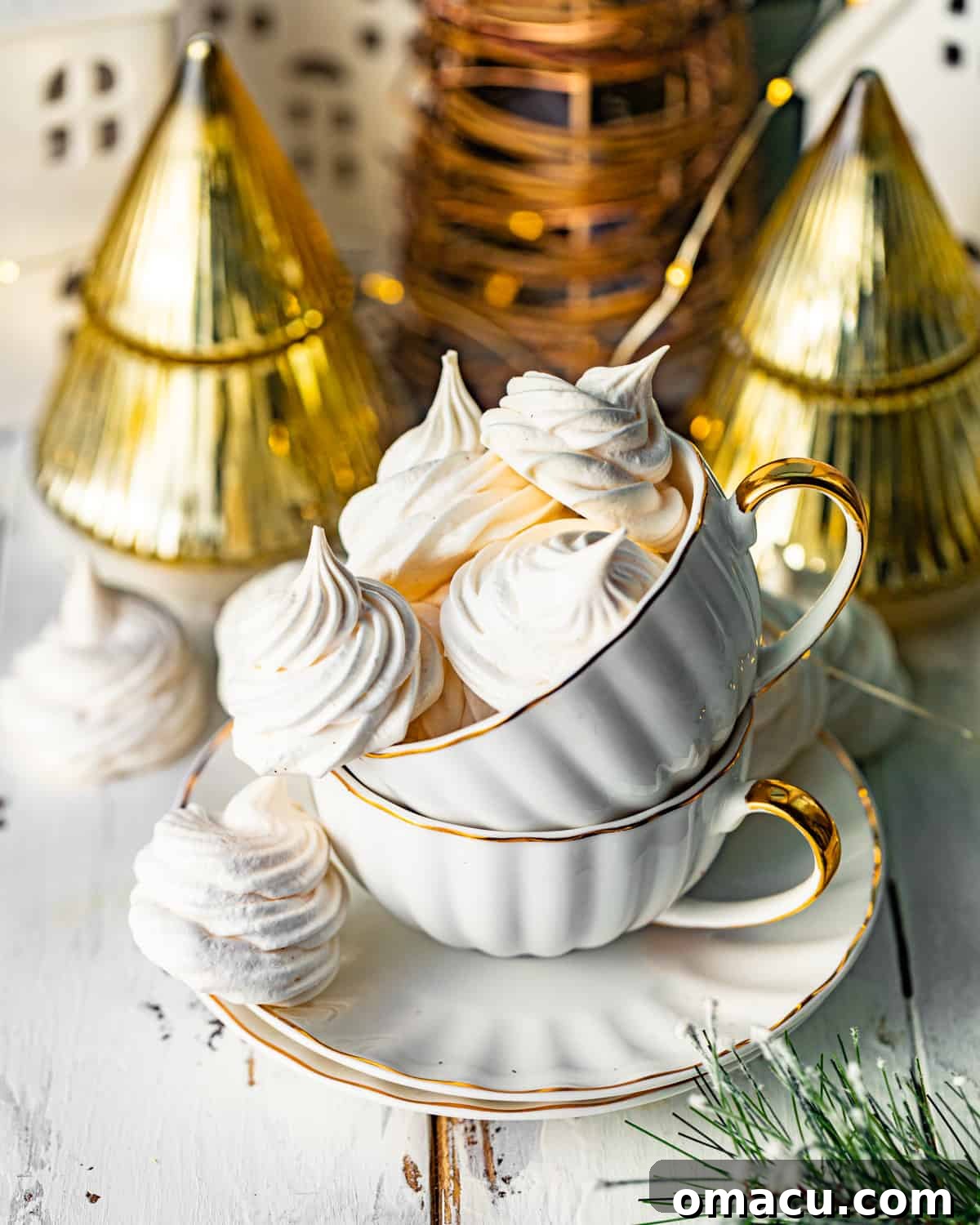 meringue cookies stacked up in teacups on a serving plate. A charming display of freshly baked meringue cookies, delicately stacked inside elegant teacups, presented on a decorative serving plate. Each cookie is perfectly formed, showcasing its light and airy texture.
