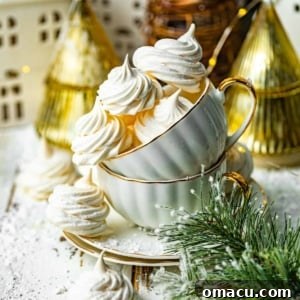 meringue cookies in a tea cup in front of a gold christmas tree. Delicate meringue cookies in a teacup against a festive gold Christmas tree.