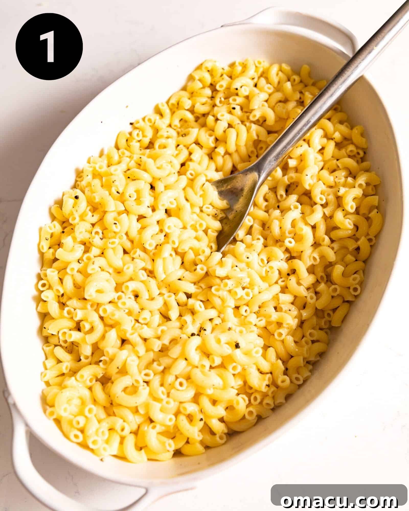 A baking dish filled with perfectly cooked elbow macaroni pasta, ready for the creamy cheese sauce and other delicious additions.