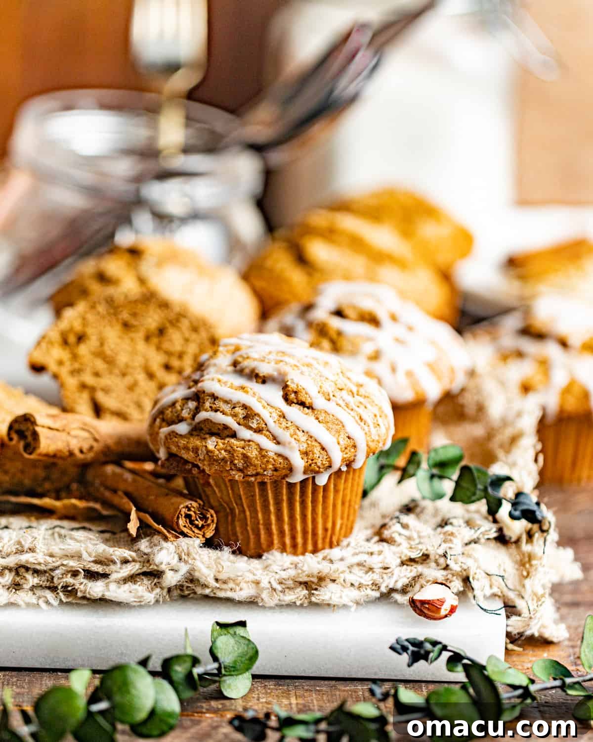 A perfectly baked gingerbread muffin sits gracefully on a crisp white tablecloth, with a vintage glass jar subtly blurred in the background, hinting at holiday charm.