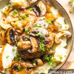 a bowl with mashed potatoes, salisbury steak, and mushroom gravy with a spoon.