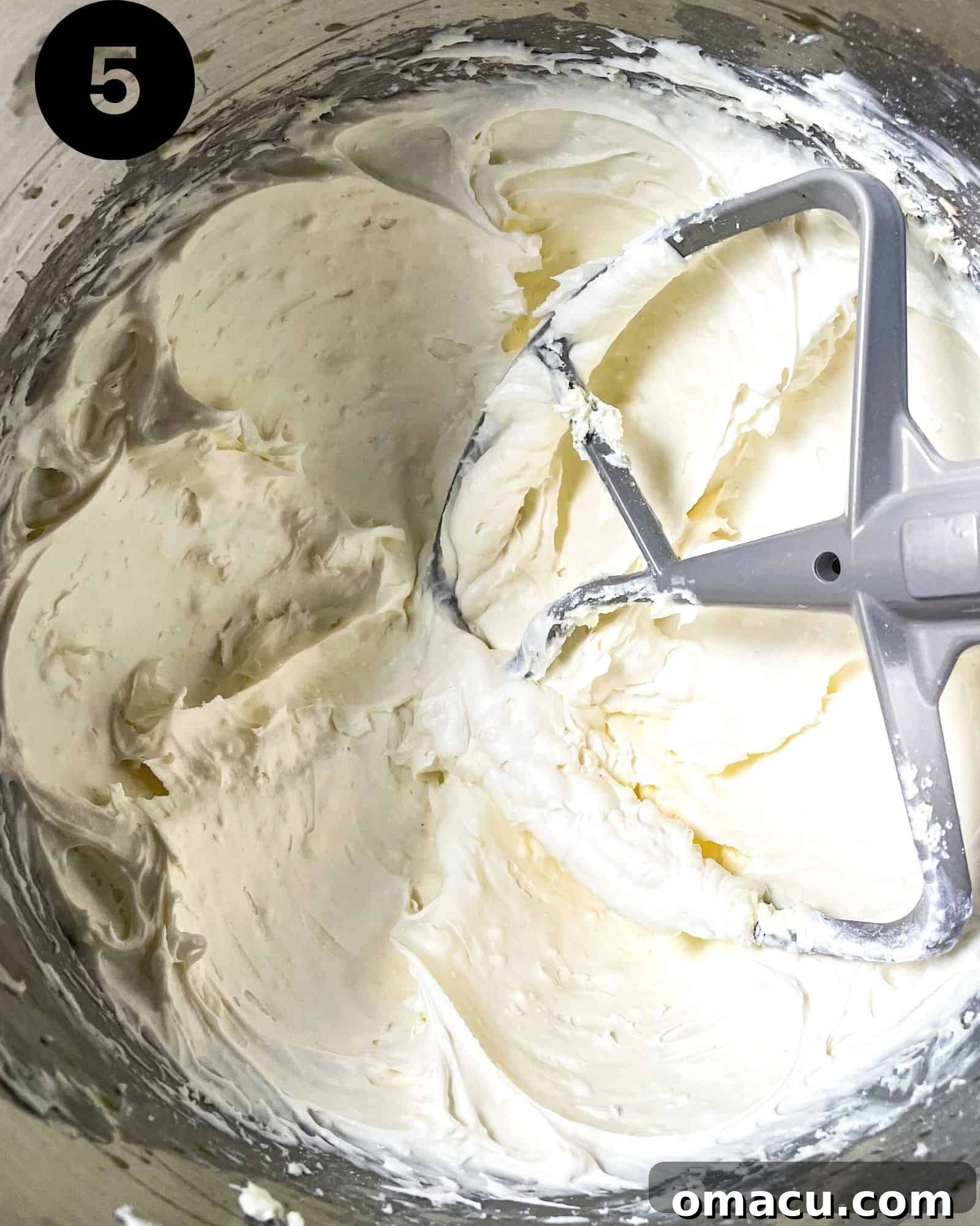 A bowl of creamy, white cream cheese frosting, perfectly whipped and ready to be spread onto the cooled red velvet brownies.
