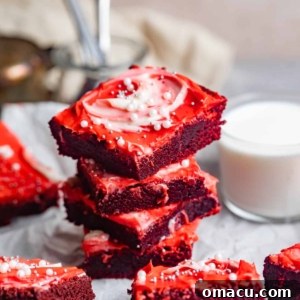 Red velvet brownies stacked on top of each other next to a glass of milk.
