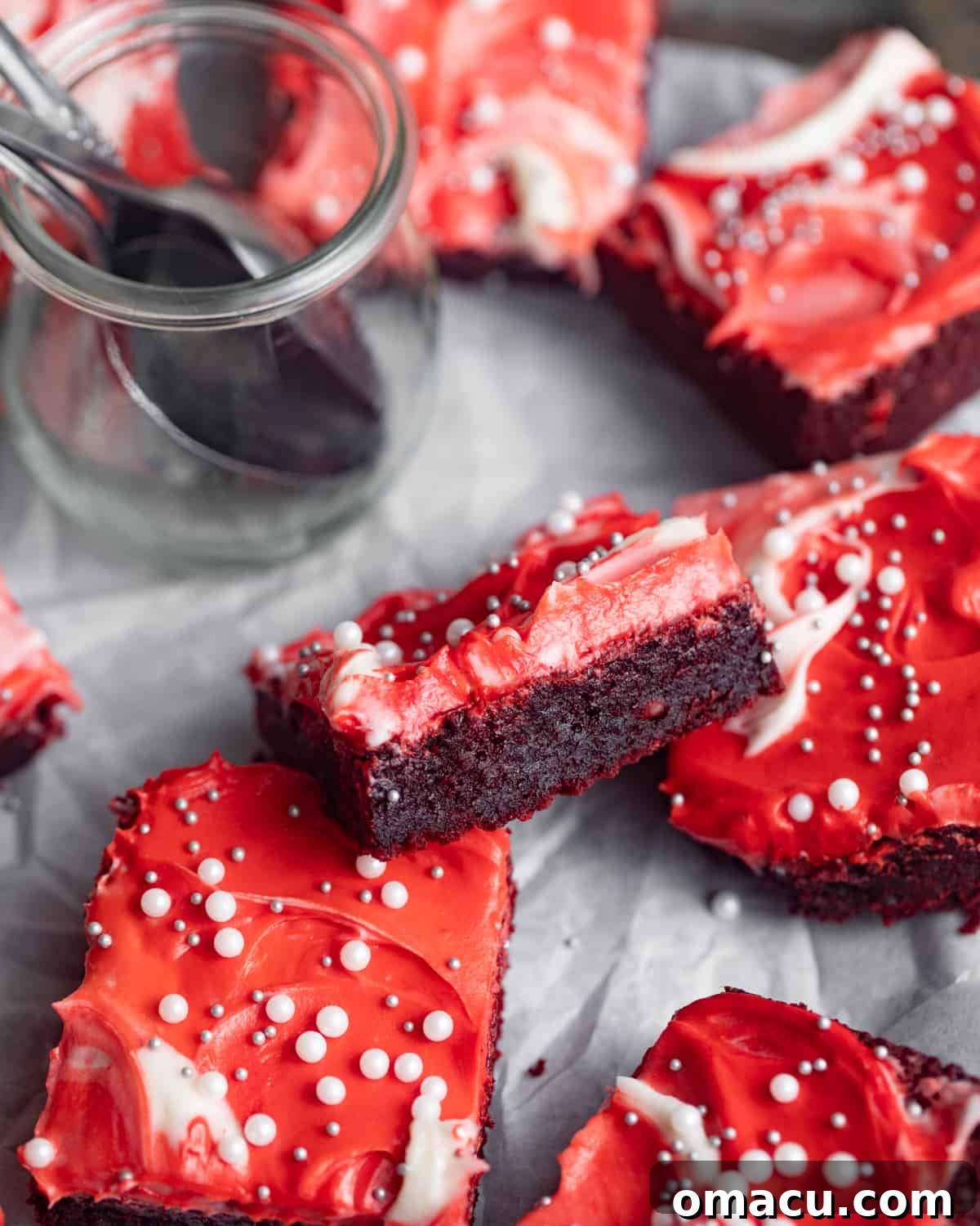 An inviting close-up of a single red velvet brownie, showcasing its moist texture and a generous swirl of luscious cream cheese frosting.